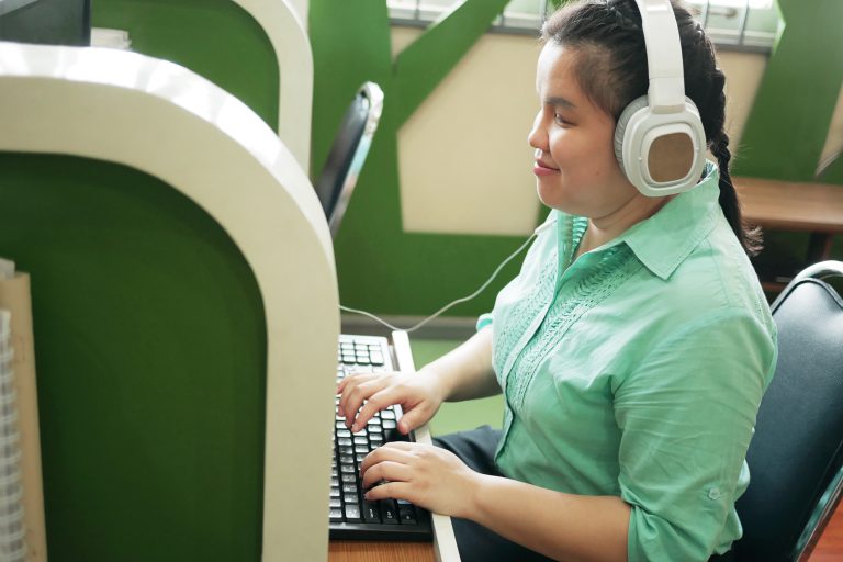 visually disabled women happily working at computer with headphones on