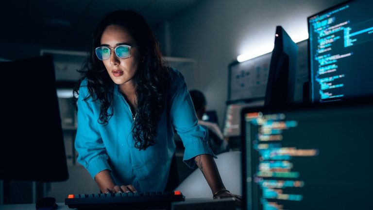 A woman coding in a dark room.