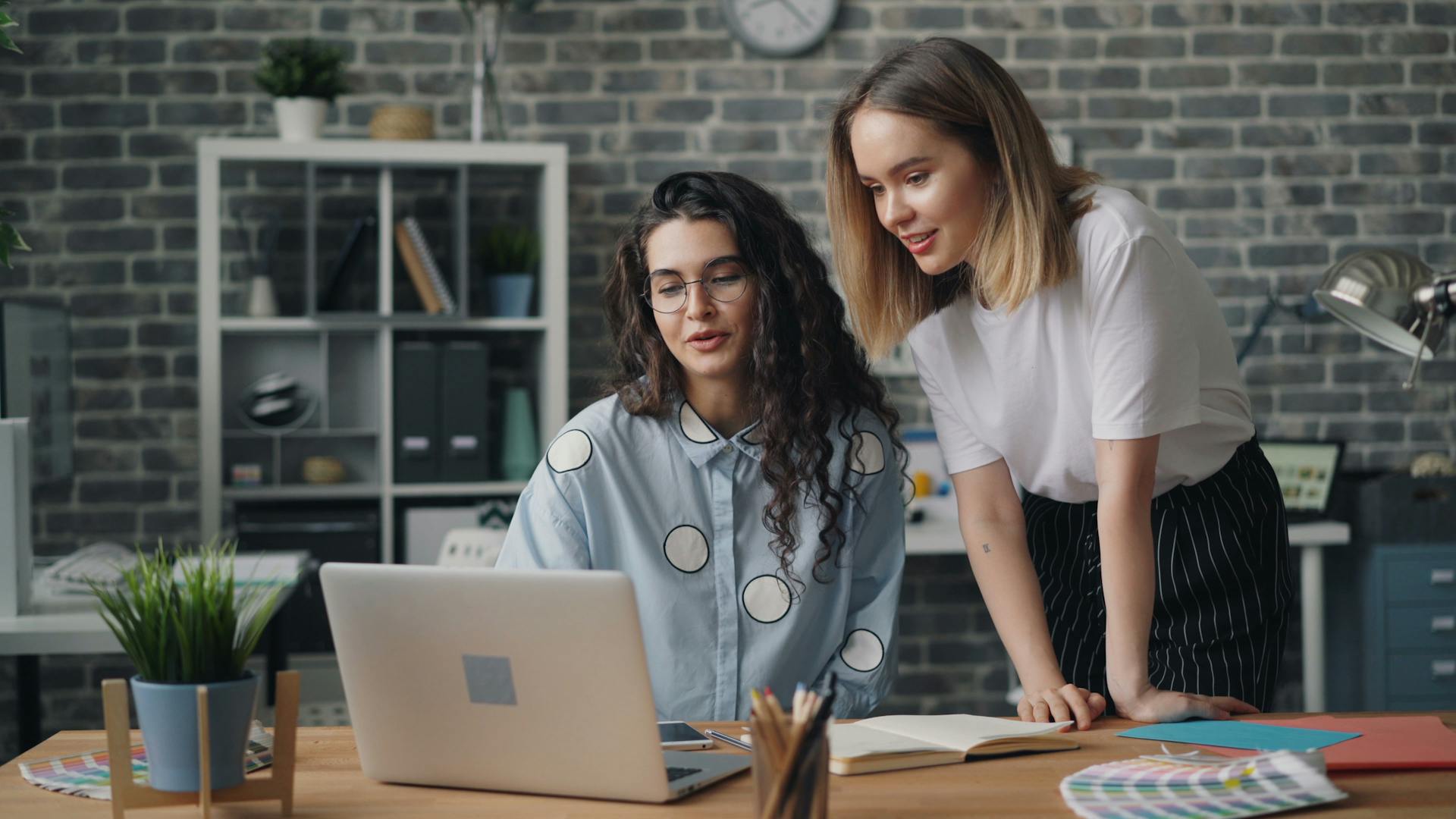 Two co-workers looking at a laptop.
